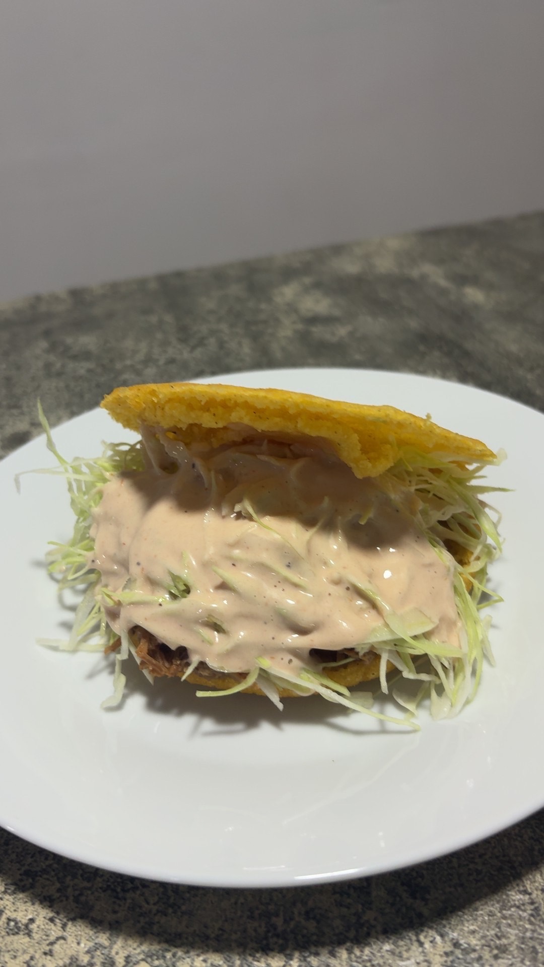 Arepa rellena de carne mechada con repollo y salsa rosada
